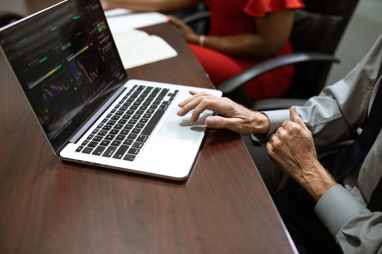 Business professionals analyzing stock market data on a laptop during a meeting.