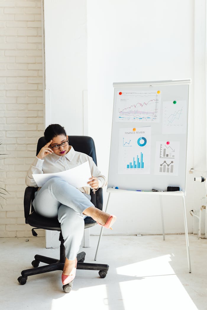 Woman analyzing financial charts and graphs in a well-lit office, suggesting business strategy development.